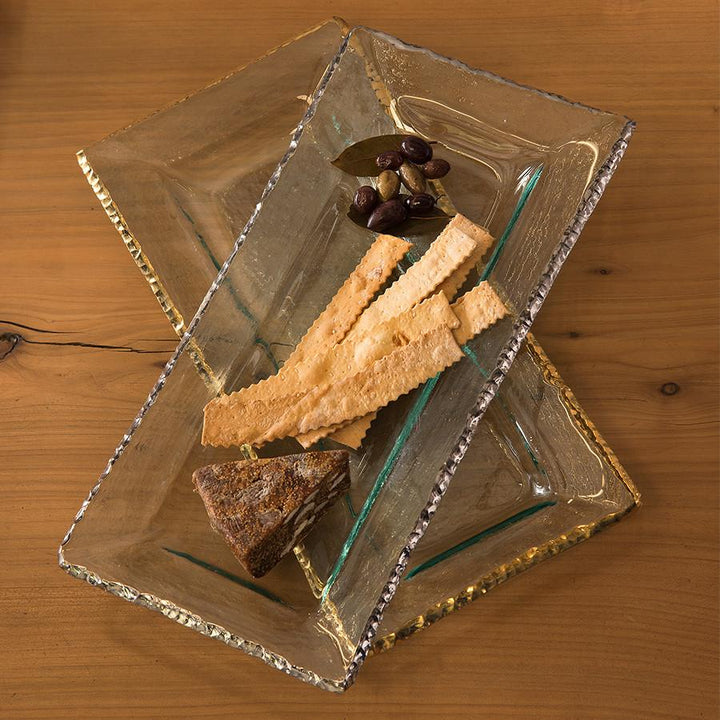 Edgey long rectangular trays one in platinum and one with a 24k gold edge with crackers, fruits and bread.