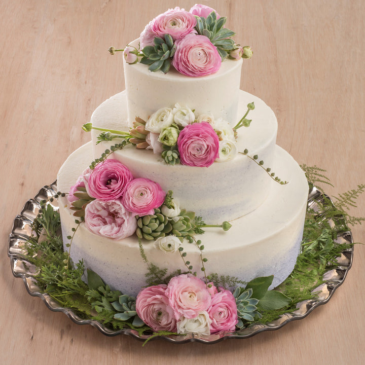 Ruffle platinum 20" round platter with a 3 layer cake and flowers.