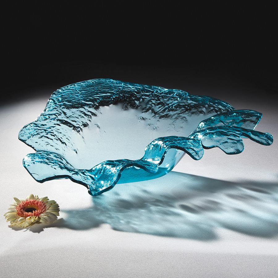 Mini splash sculpture made in ultramarine glass with a flower as decoration next to it.