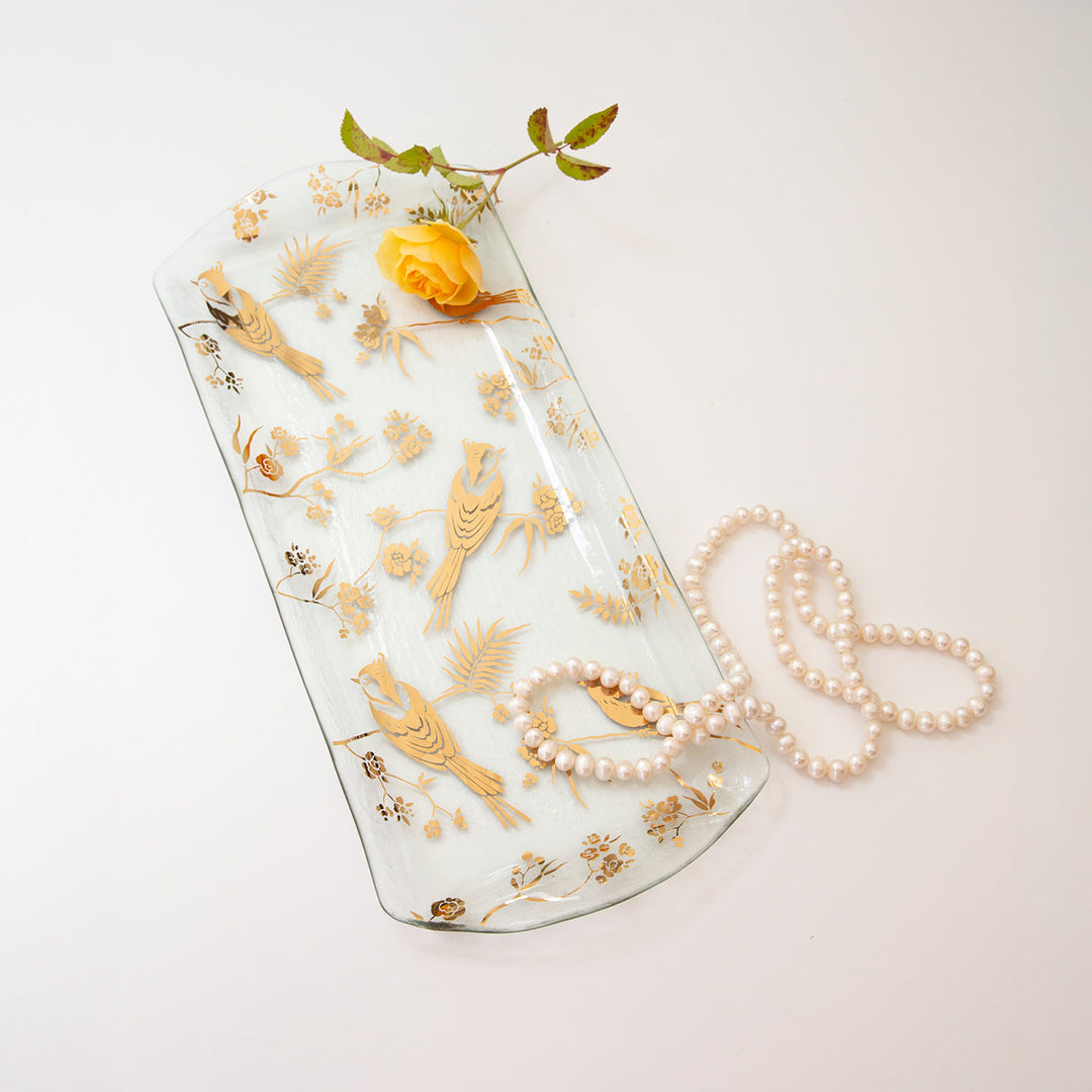 Clear rectangular glass with 24k gold birds and branches with a pearl necklace and a yellow rose. 