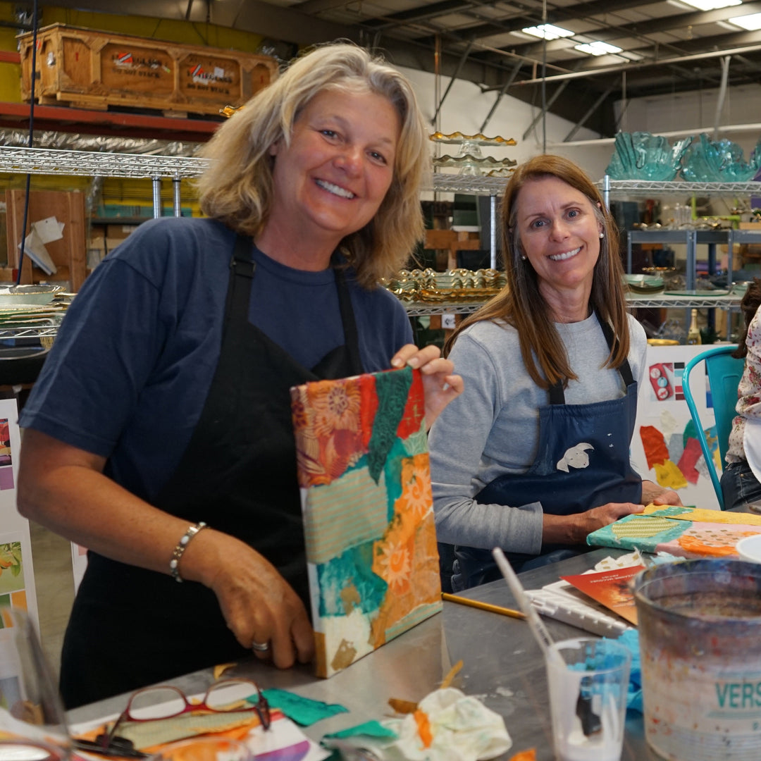 Three women in aprons working on art projects in a studio setting.