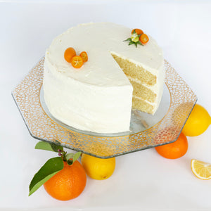 Cake stand with a mosaic band and a white cake with lemons and oranges.