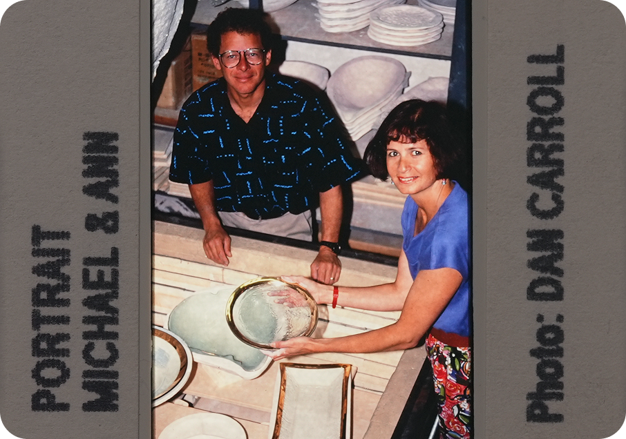 Portrait of Michael & Annie in 1983, sitting at a table with different molds and glass pieces.