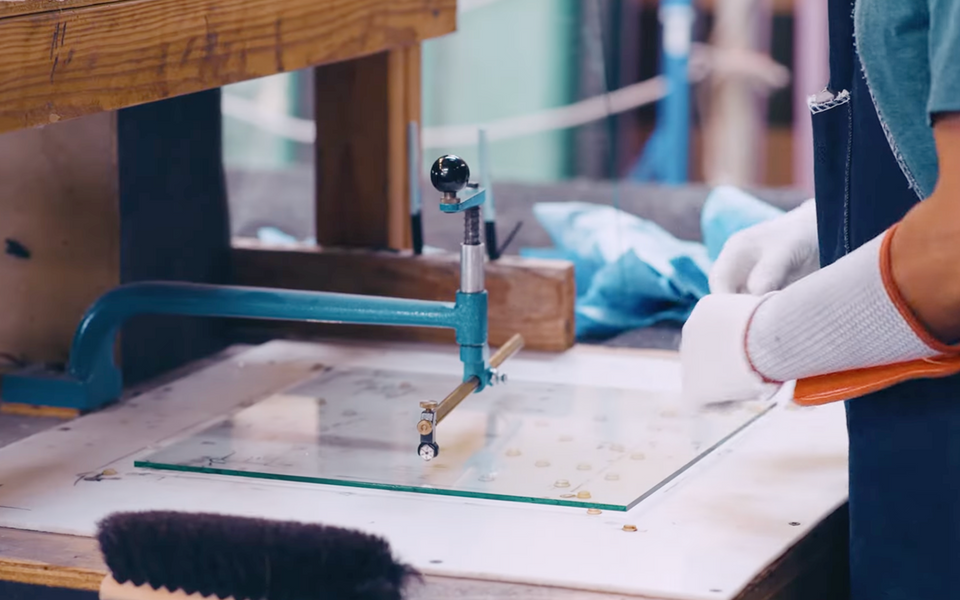 worker using circle cutter on sheet glass