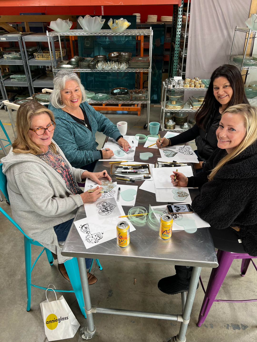 Four women sitting around a table in a workshop setting, engaged in heart ornament workshop