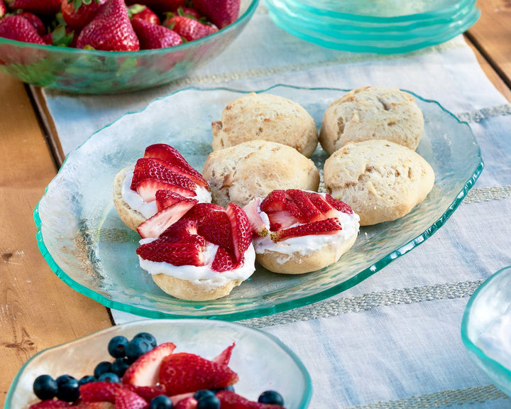 Placed on a wooden table with a cloth runner, homemade strawberry shortcakeks are served on a Salt Oval Tray.
